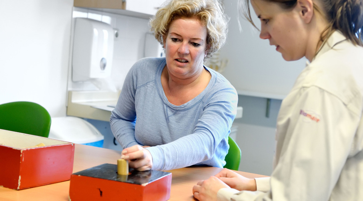 Ergotherapeut geeft aanwijzingen aan patiënt tijdens handtraining